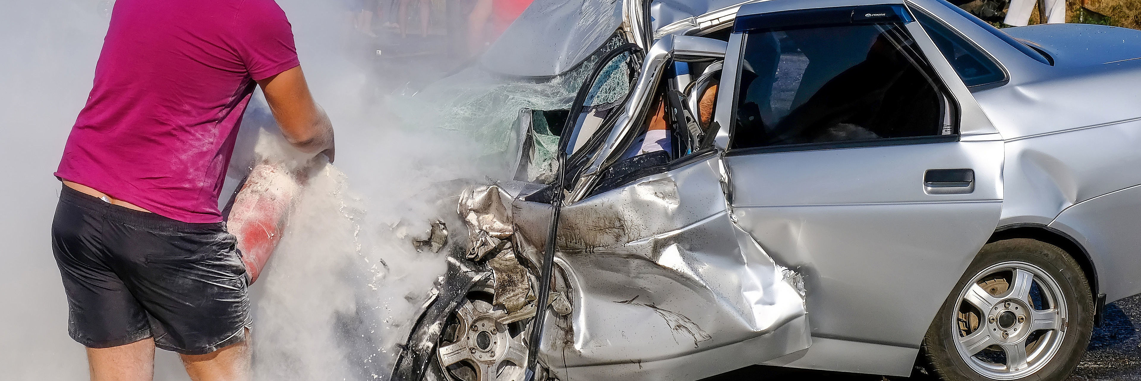 Man extinguishes the car with a fire extinguisher. Damaged vehic